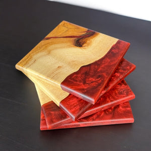 Dragon epoxy resin and Hickory wood coasters sitting on a black wood table.