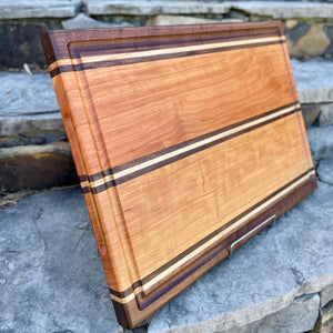 A beautiful cherry cutting board with maple and walnut inlays.