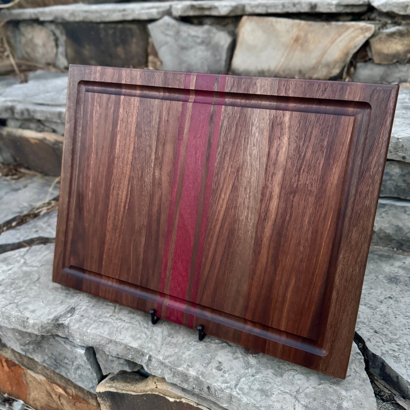 Walnut Cutting Board with Purpleheart inlays. This board has a juice groove and finger groove, with a stone background.