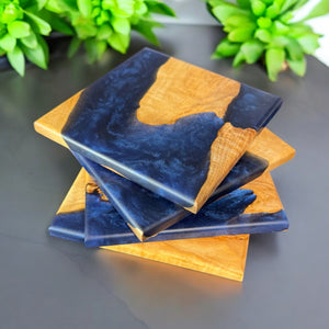 Midnight epoxy resin and maple wood coasters on a gray countertop.