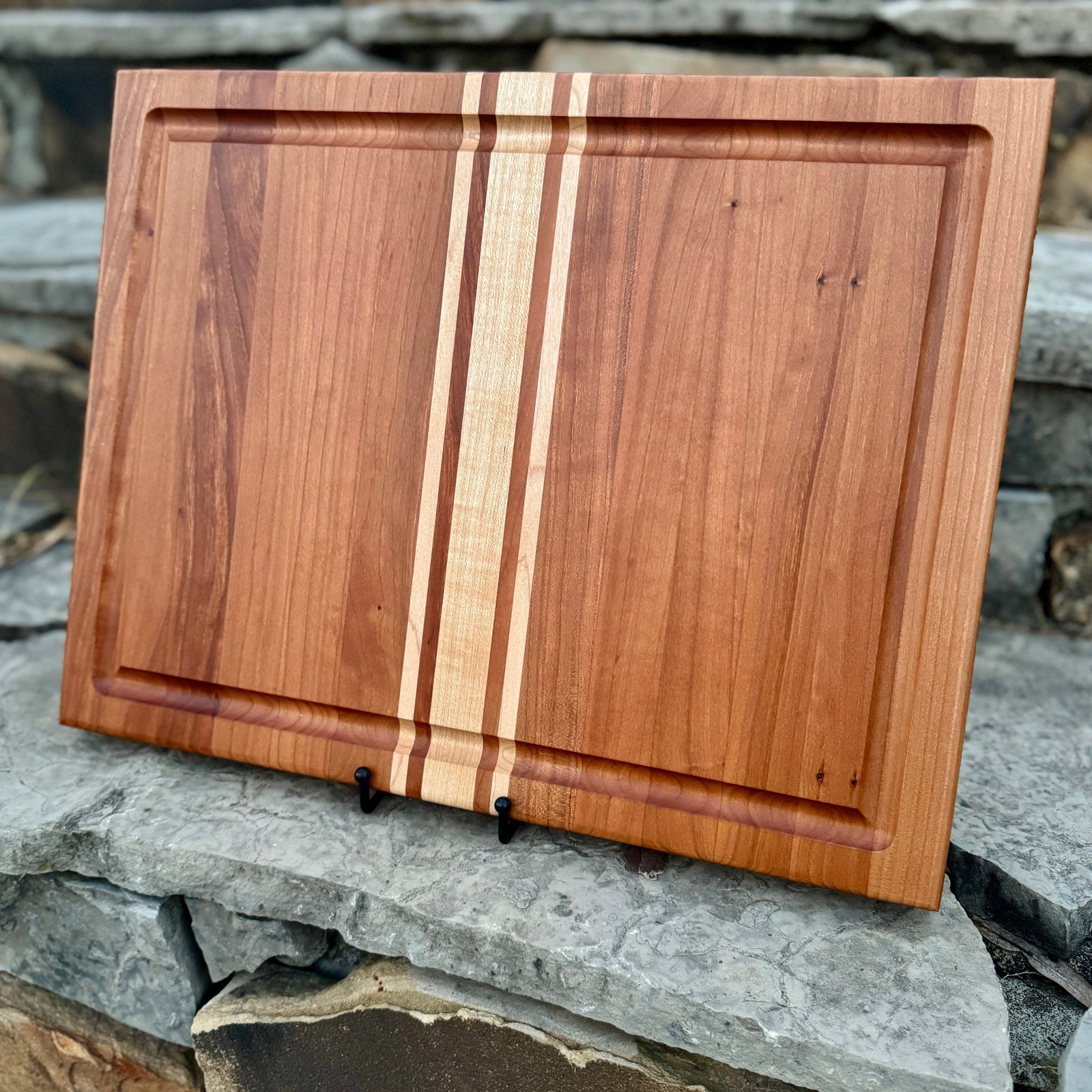 Cherry Cutting Board with Maple Inlays,  this cutting board has a juice groove and finger grooves with a stone background.