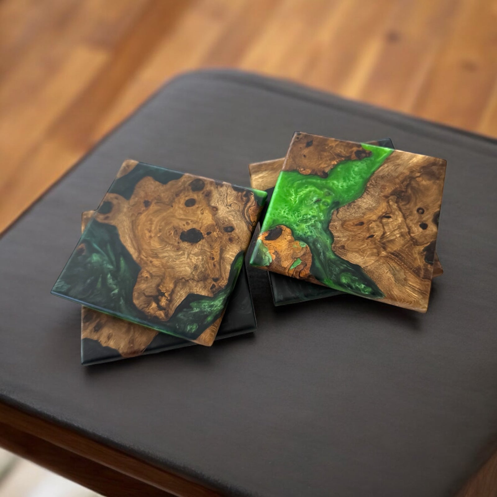 Maple burl coasters with a swirling green resin, sitting on a side table.