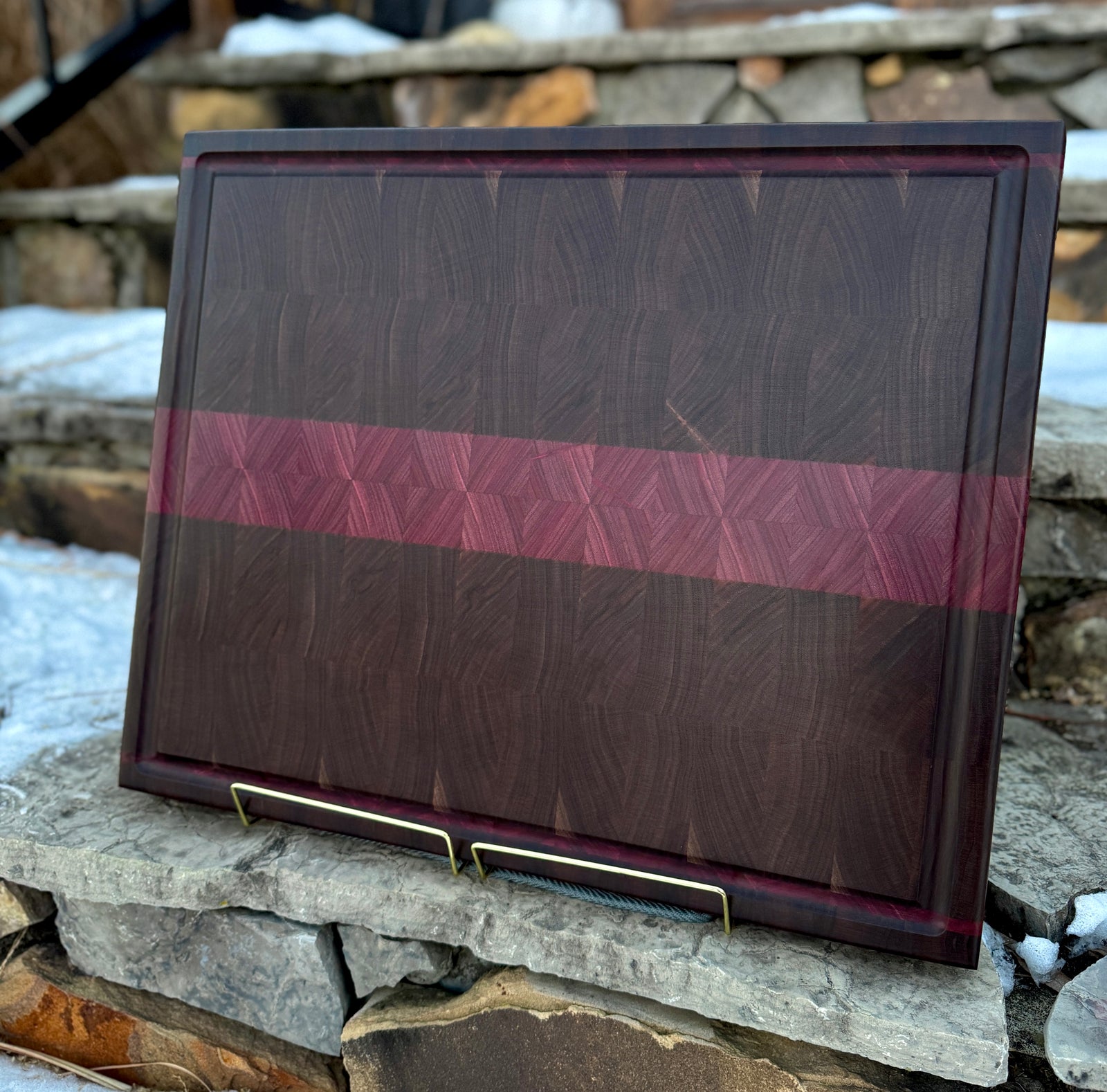 A walnut end grain cutting board with end grain purpleheart inlays with a stone background