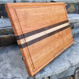 A side view of a cherry cutting board, you can see the juice groove and the finger grooves.