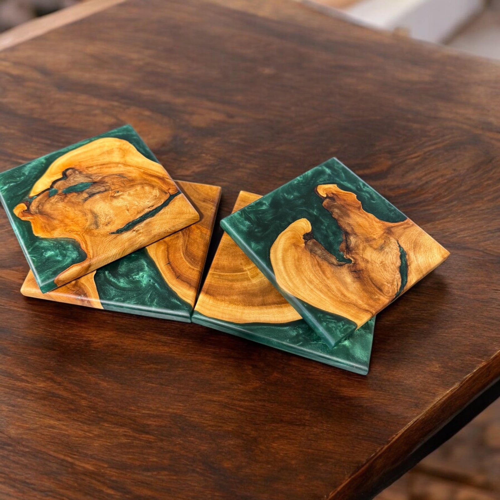 Maple Burl Coasters with Emerald Resin sitting on a walnut end table.