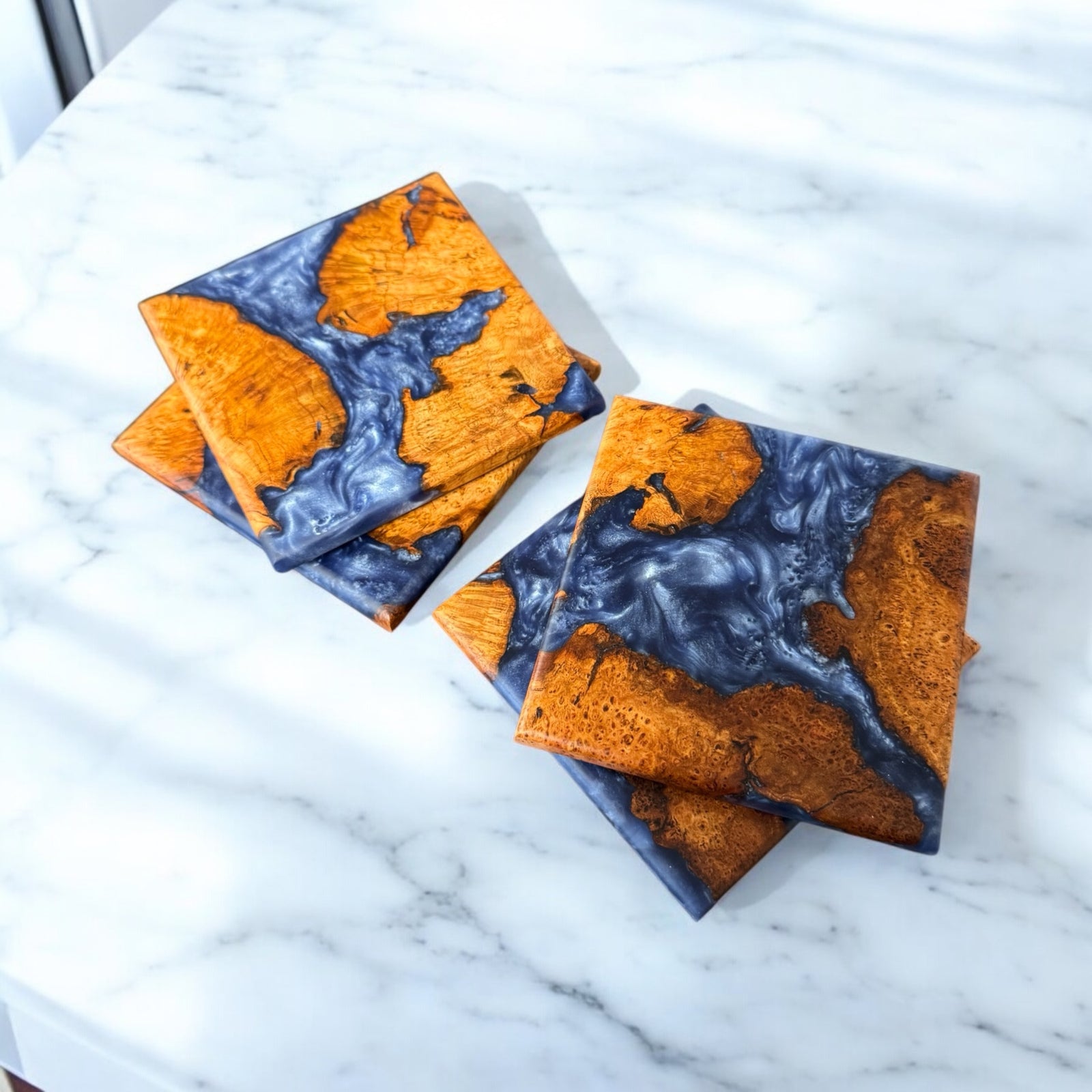 Cherry Burl coasters with silver blue resin, sitting on a white marble countertop.