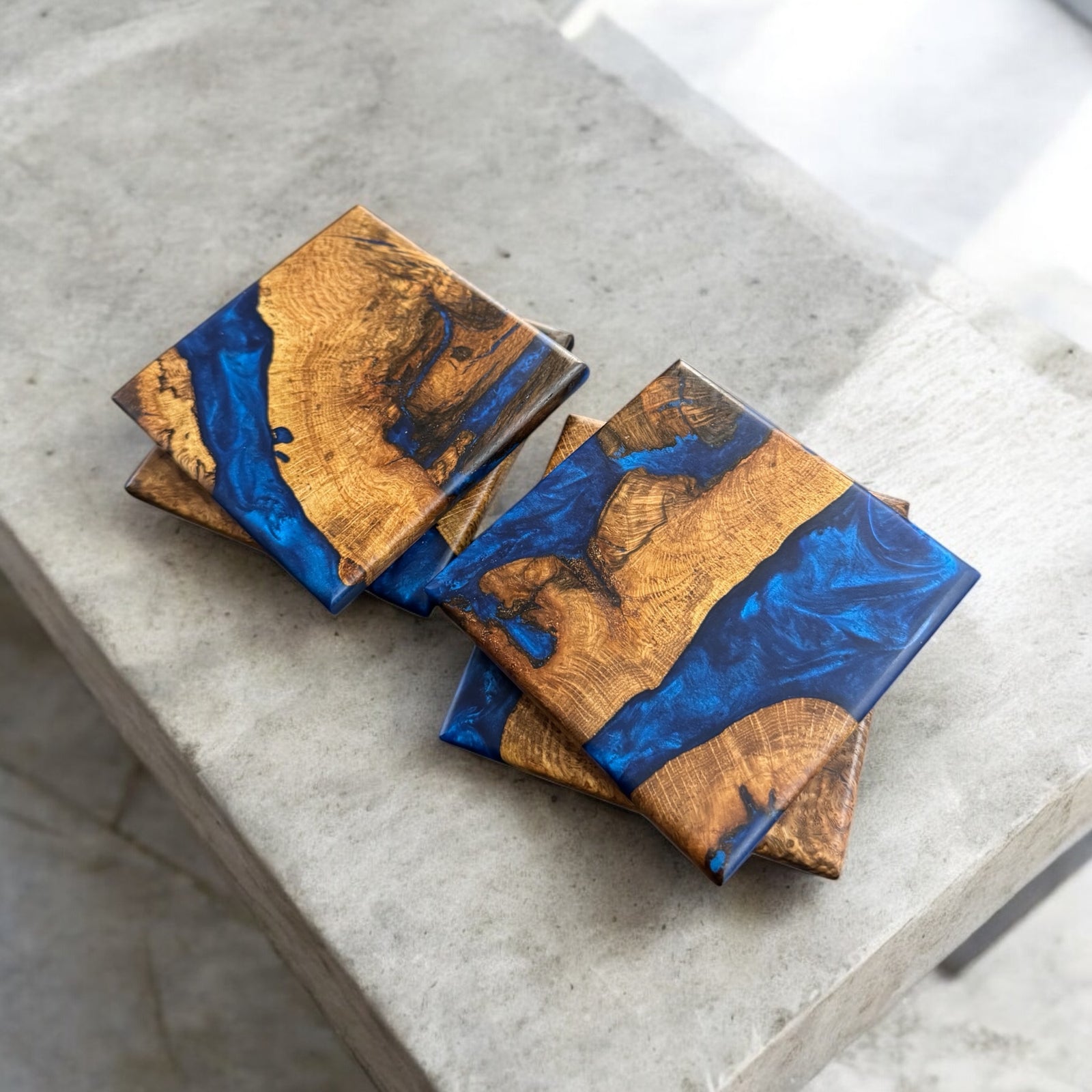 Oak Burl Coasters with Pacific Blue resin sitting on a concrete table.