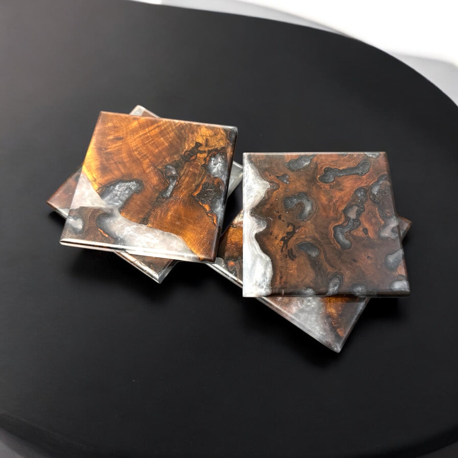 walnut burl coasters with ghost resin sitting on a black end table.