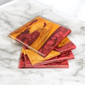 Wine epoxy resin and Maple wood coasters sitting on a marble countertop.